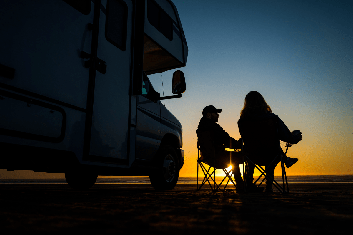 Man and woman sitting in folding chairs outside of an RV